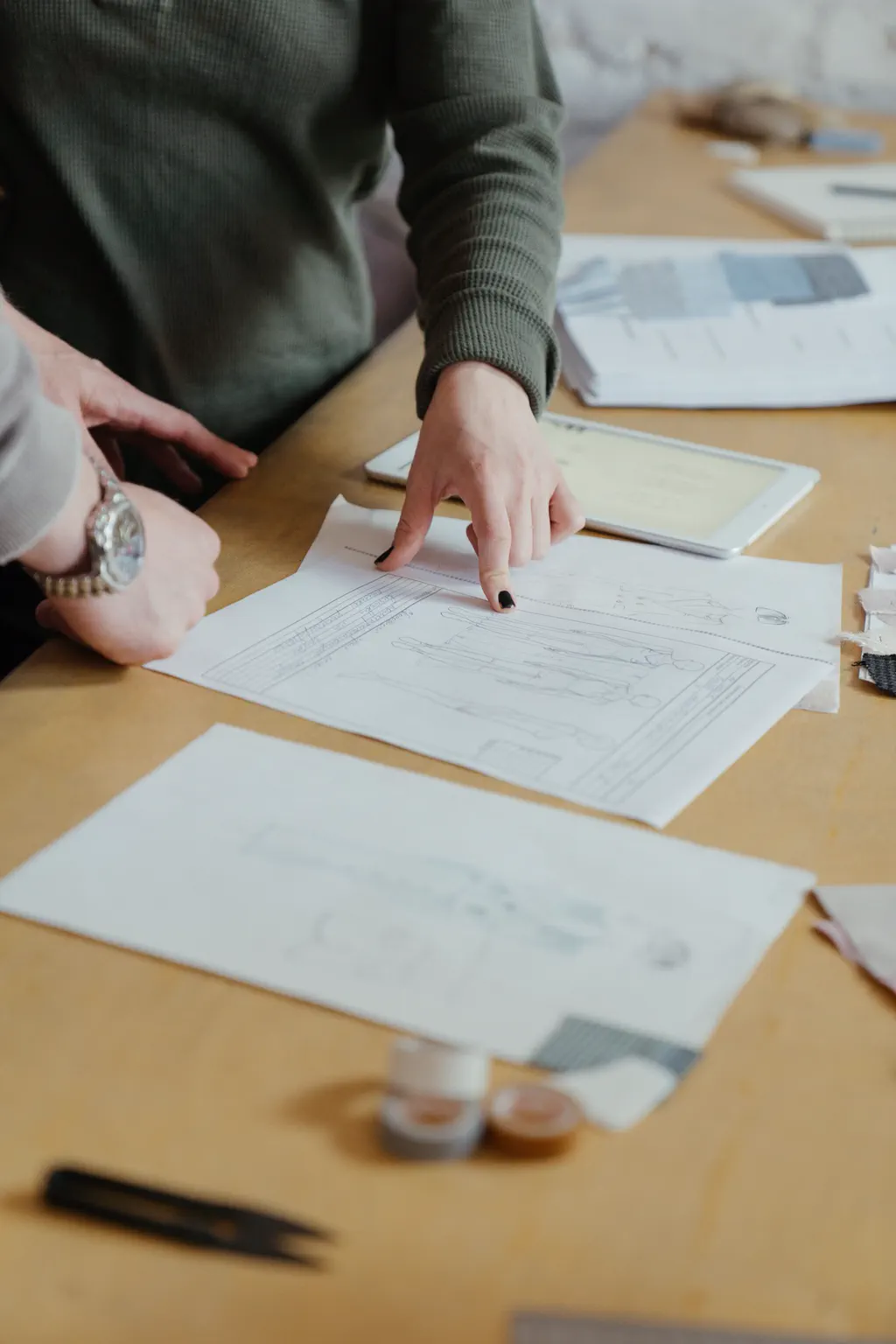 Two collaborators reviewing design plans at a worktable
