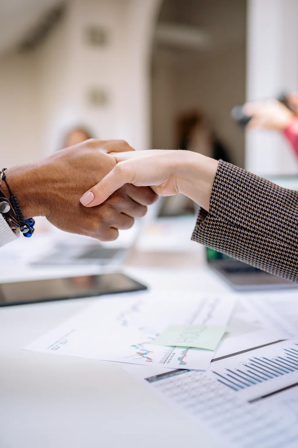 Two collaborators shaking hands over project documents