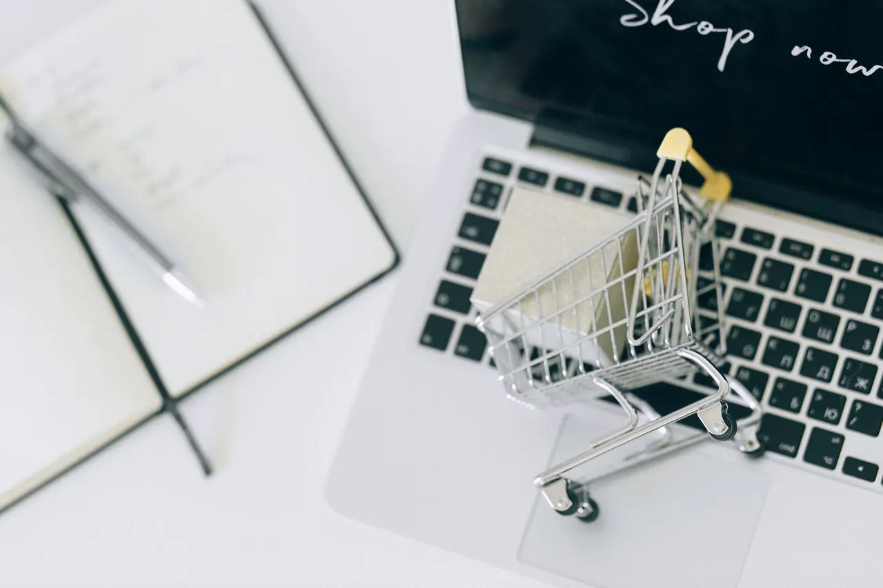 A miniature shopping cart resting on a laptop keyboard