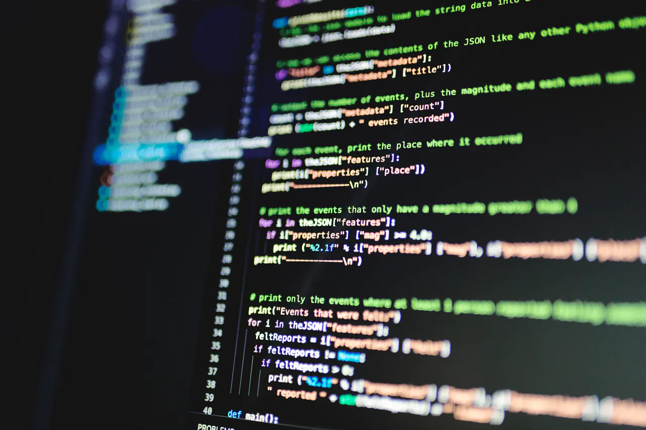 Software code displayed across two dark monitors